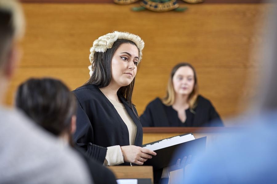 A student wearing a robe and wig in a moot court