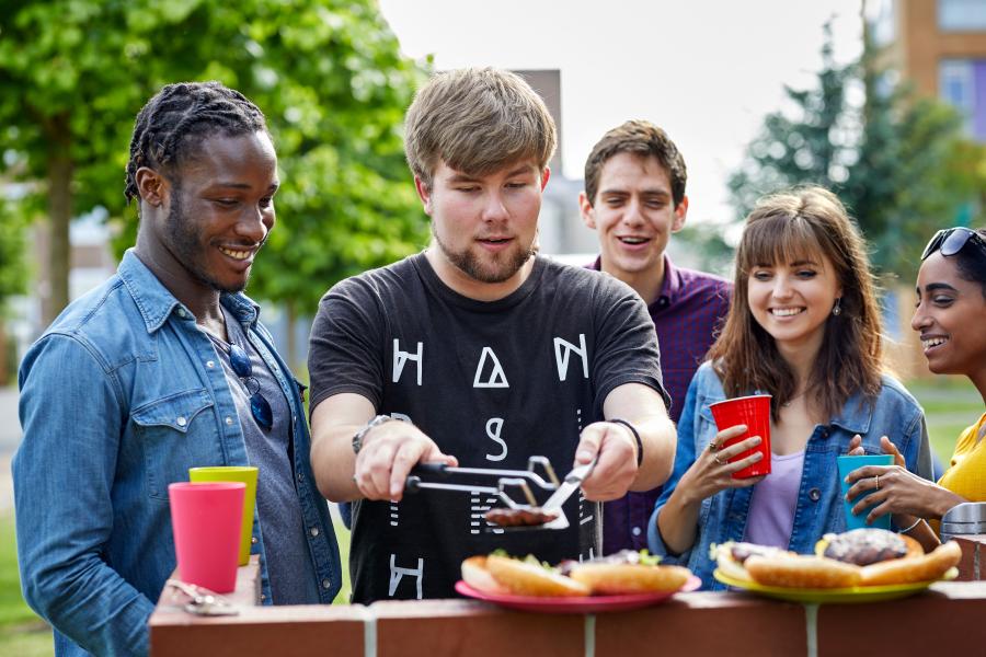 A group of students enjoying a BBQ outside halls of residence at the Ffriddoedd Student Village