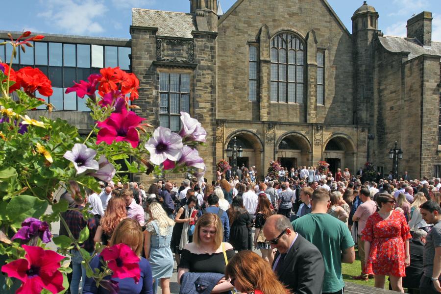 Students and friends and family gather outside the University's Main Arts building on graduation day
