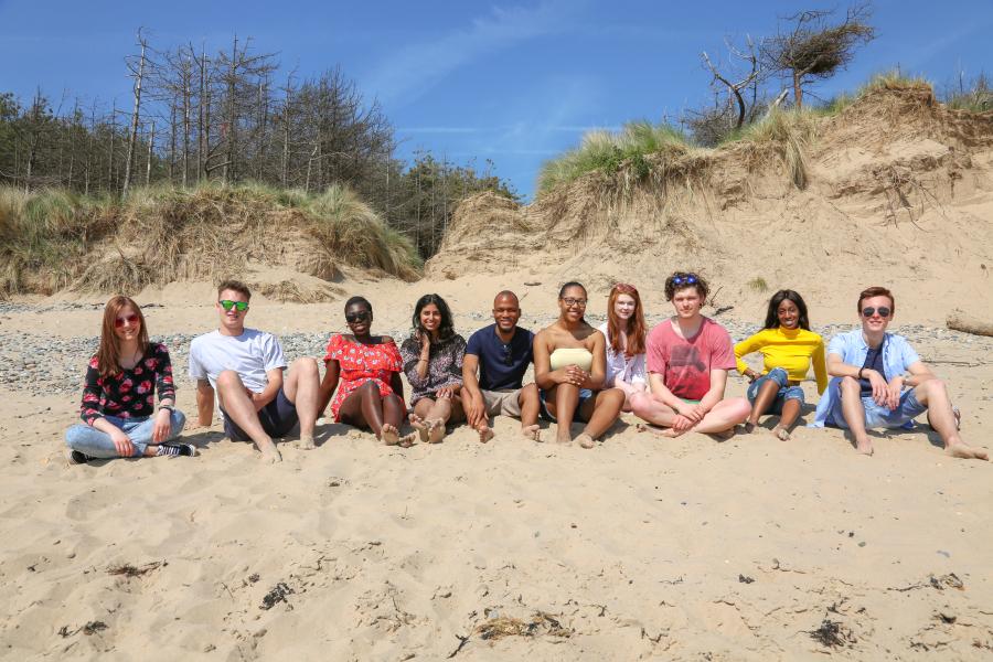 A group of students all sat together on the beach